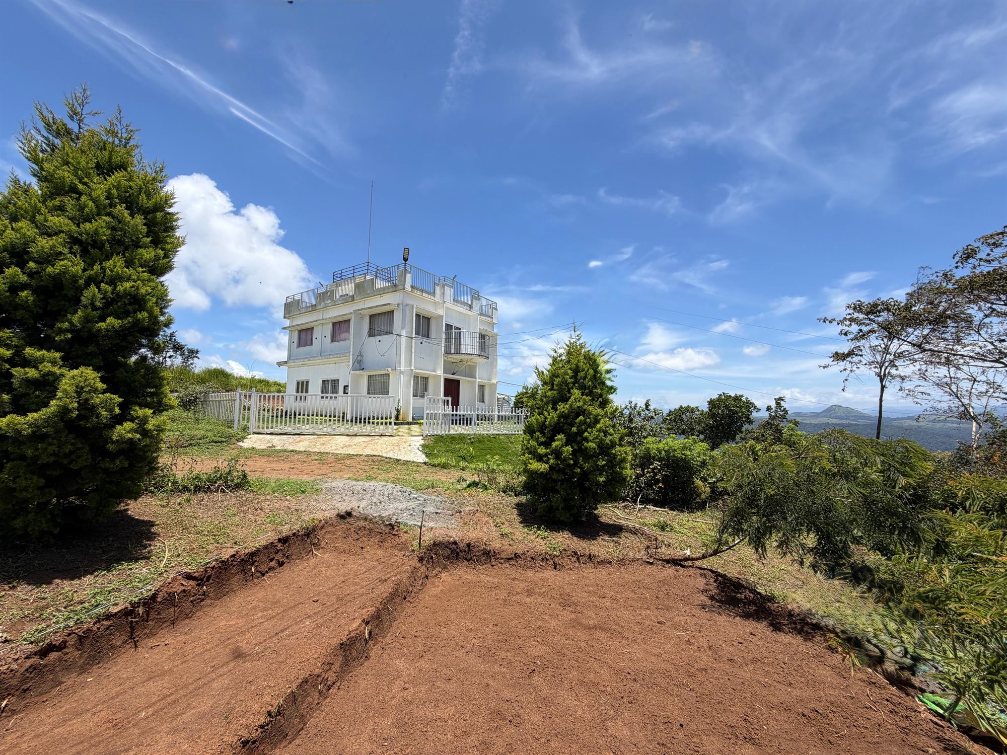 Elaichi Hills home stay building on a hilltop under a clear blue sky, surrounded by greenery